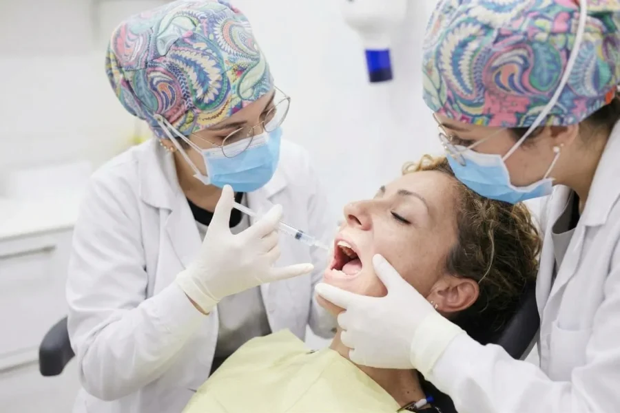 Doctoras preparando la infiltración de anestesia dental en el área peribucal de una paciente en la clínica..