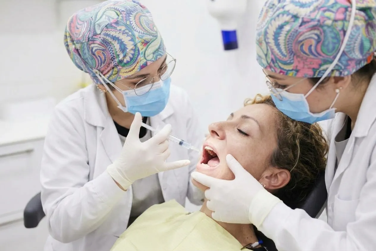 Doctoras preparando la infiltración de anestesia dental en el área peribucal de una paciente en la clínica..